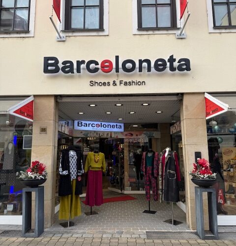 Schaufenster eines Modegeschäfts mit bunter Kleidung und Dekorationen.