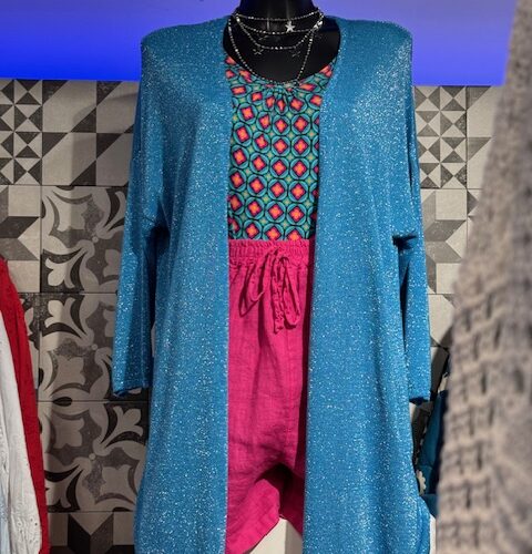 Schaufensterpuppe trägt strahlendes blaues Outfit mit geometrischen Mustern und pinken Shorts.