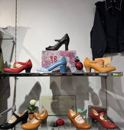 Ein Regal mit bunten Damenschuhen und einer Bluse auf einem Bügel. Schöne Präsentation.